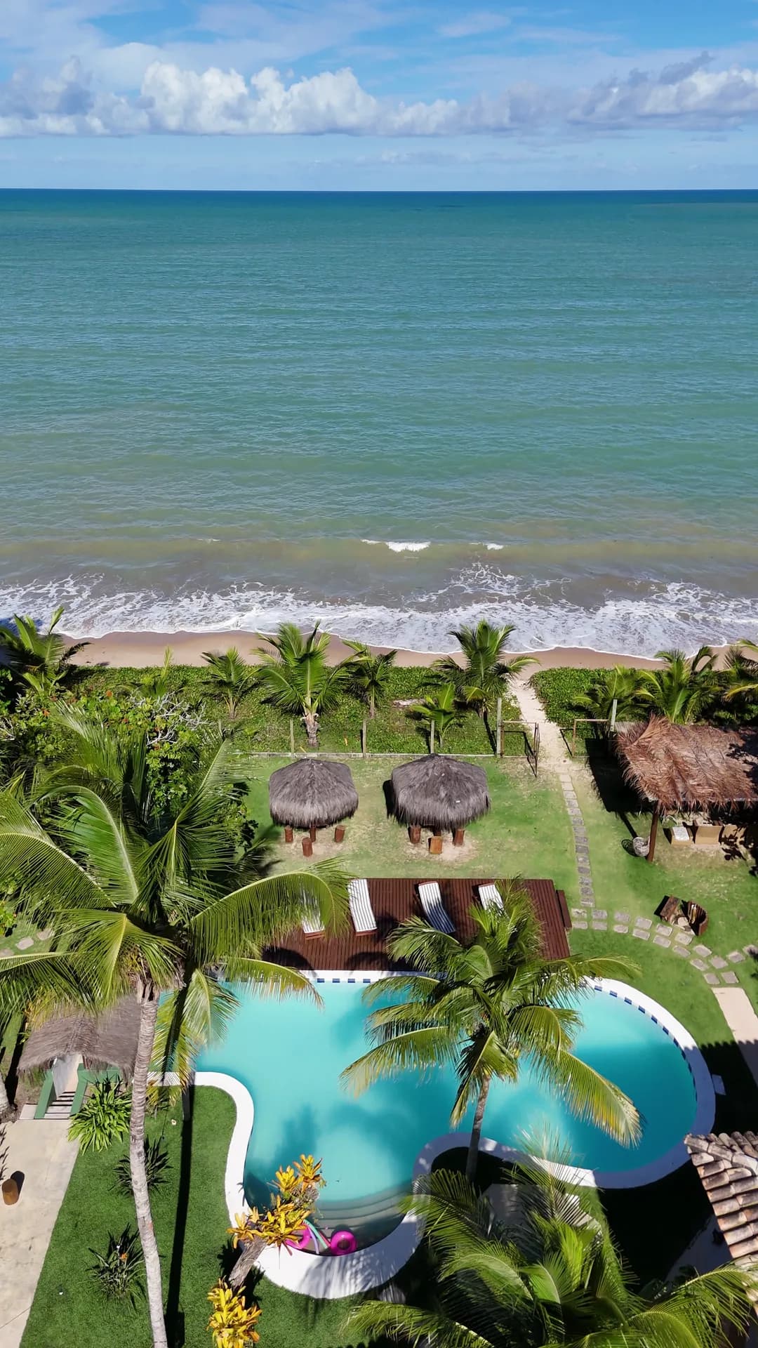 Vista aérea da piscina e do jardim da Mayon, com acesso à praia e o mar à frente