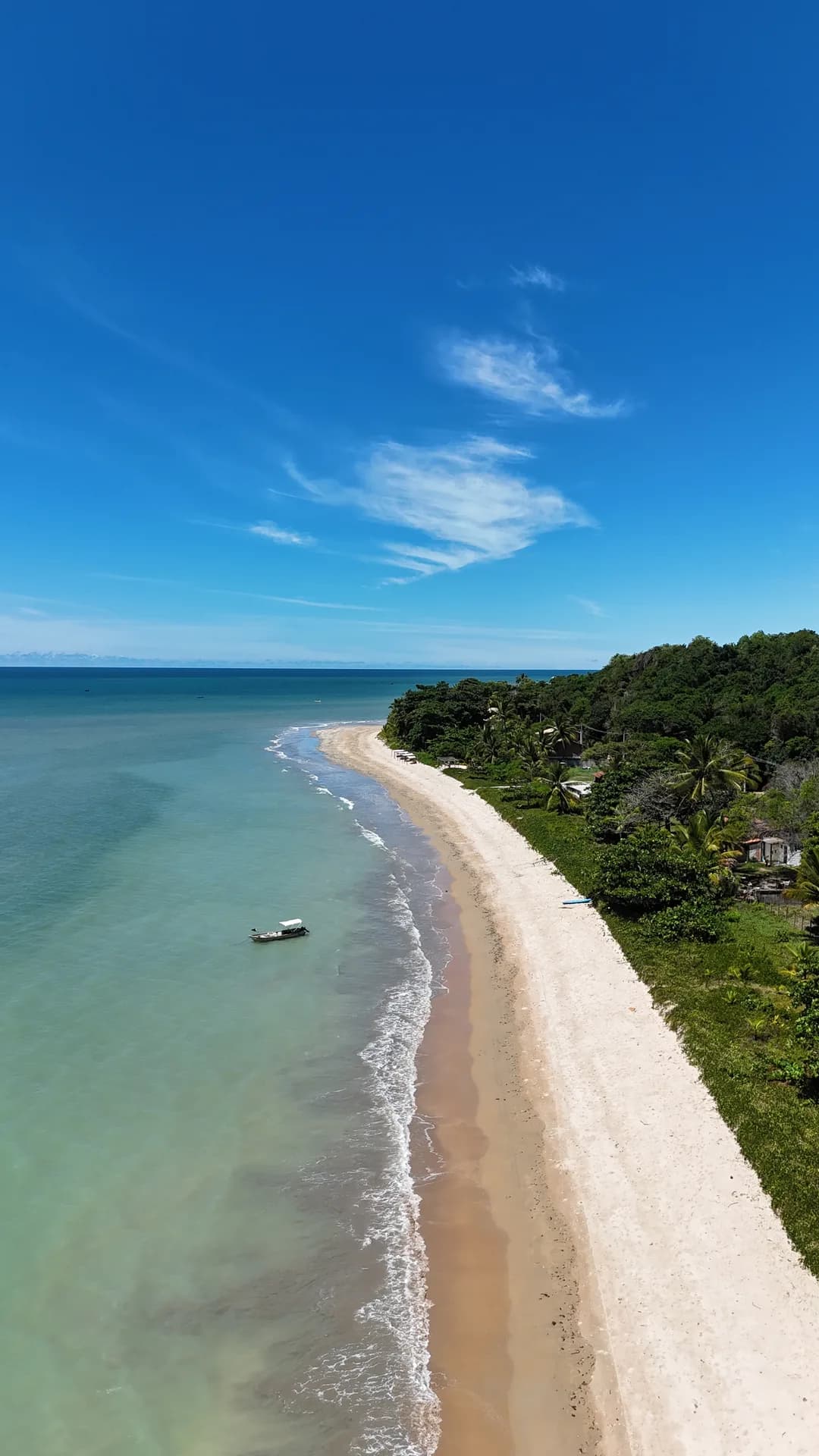 Faixa de areia entre o mar e a vegetação no litoral de Cumuruxatiba