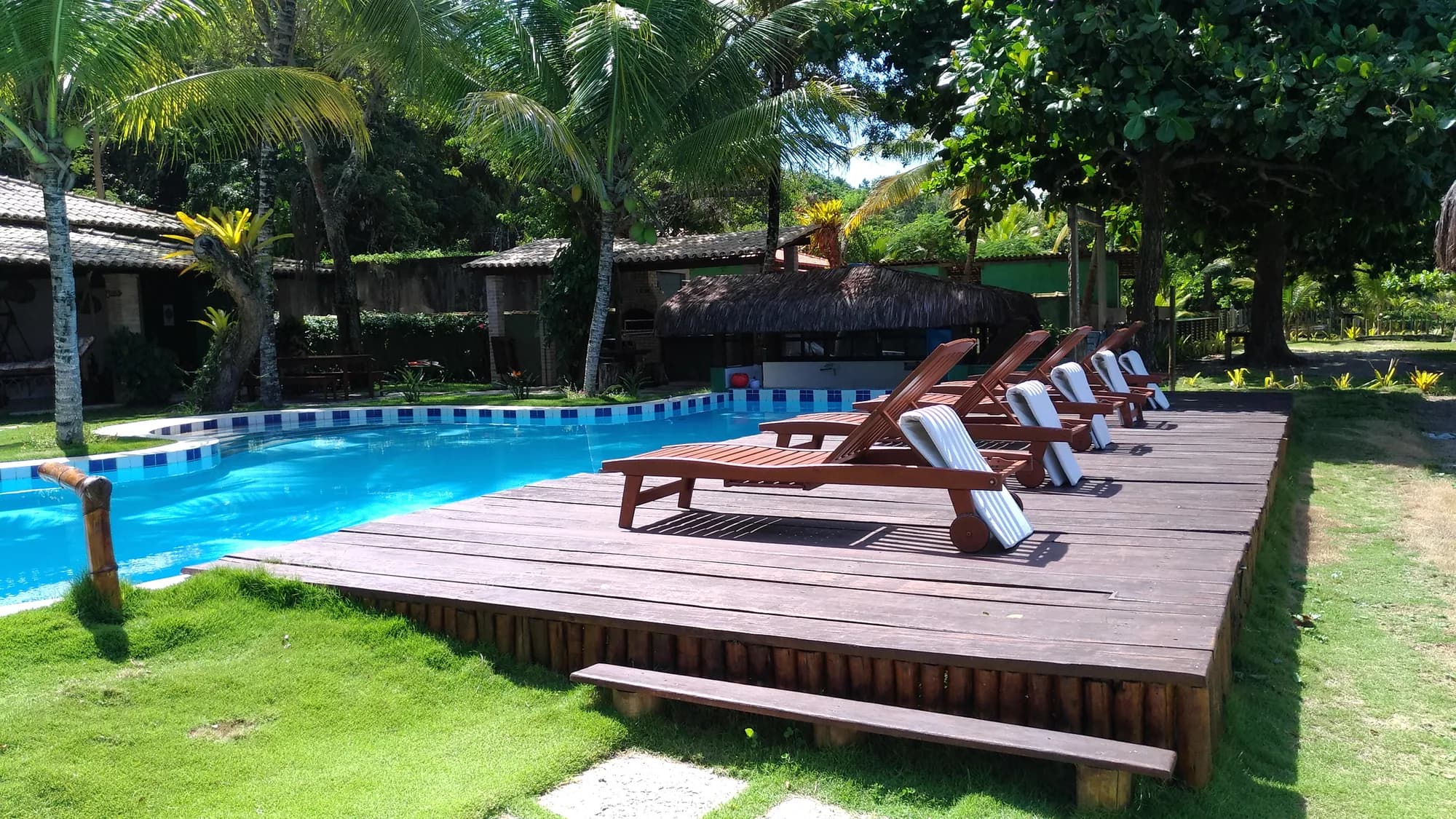 Deck com espreguiçadeiras à beira da piscina da Pousada Mayon