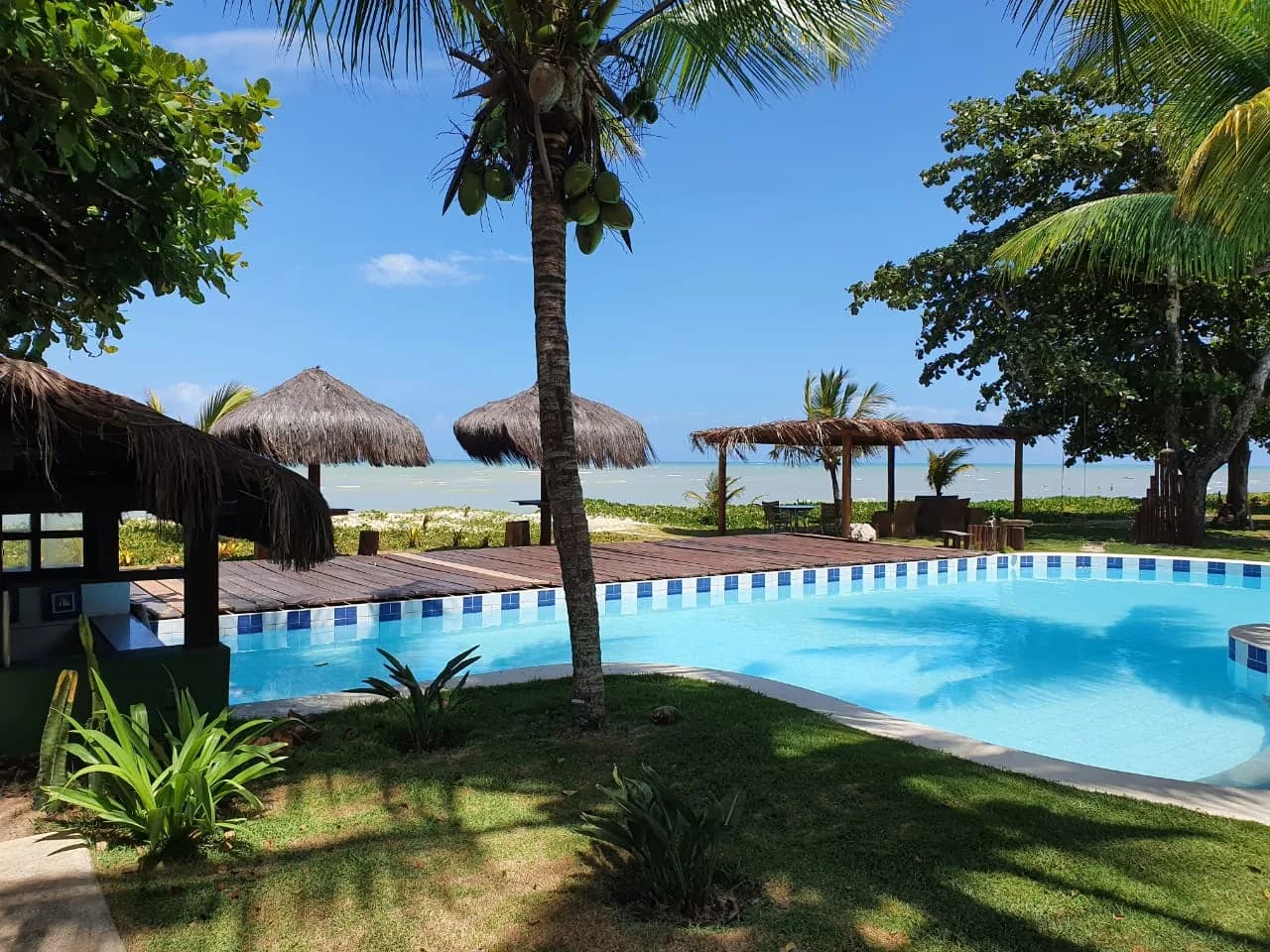 Piscina da Pousada Mayon com quiosques e o mar ao fundo