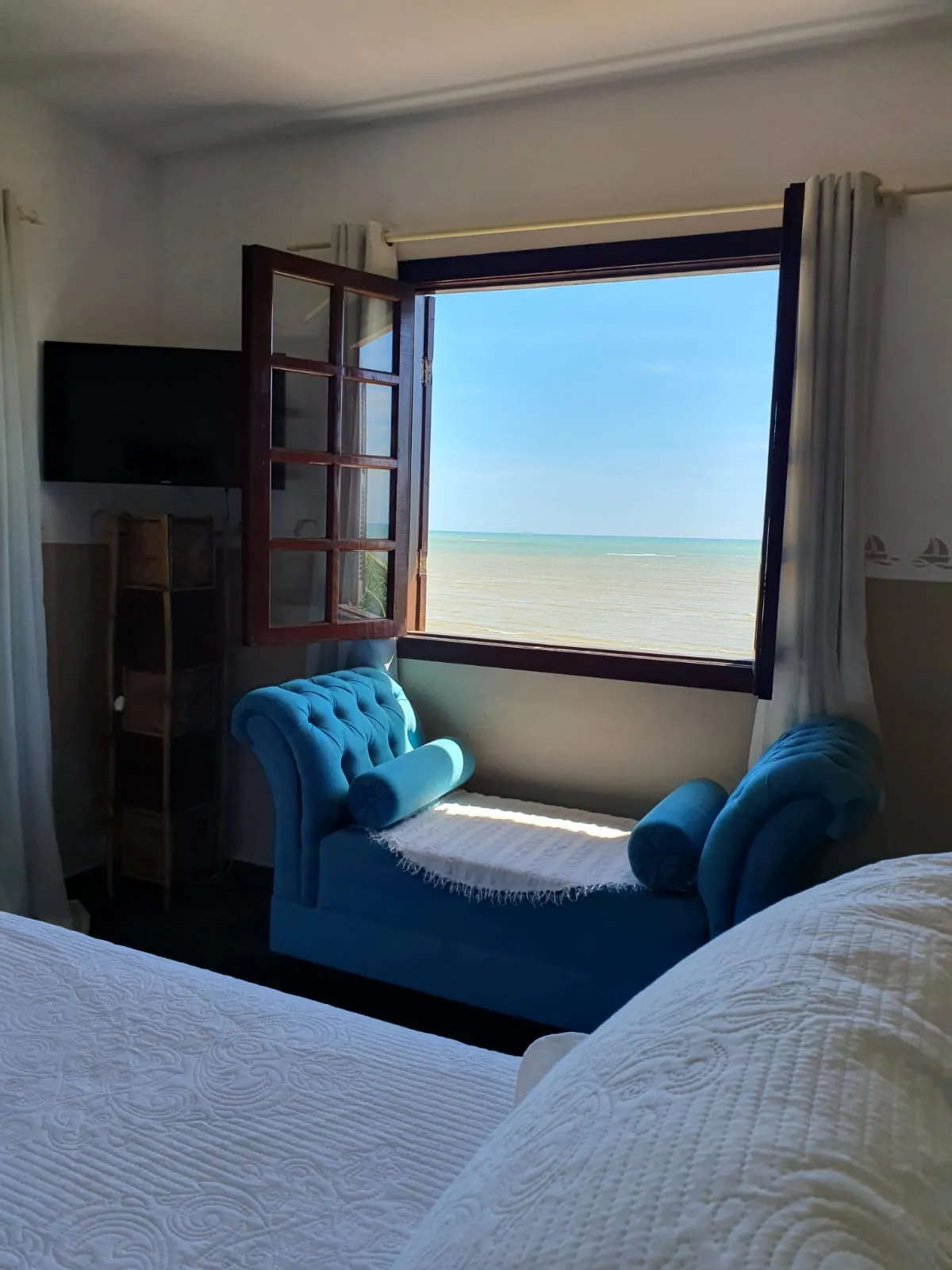 Janela da Suíte 8 com vista para o mar e poltrona