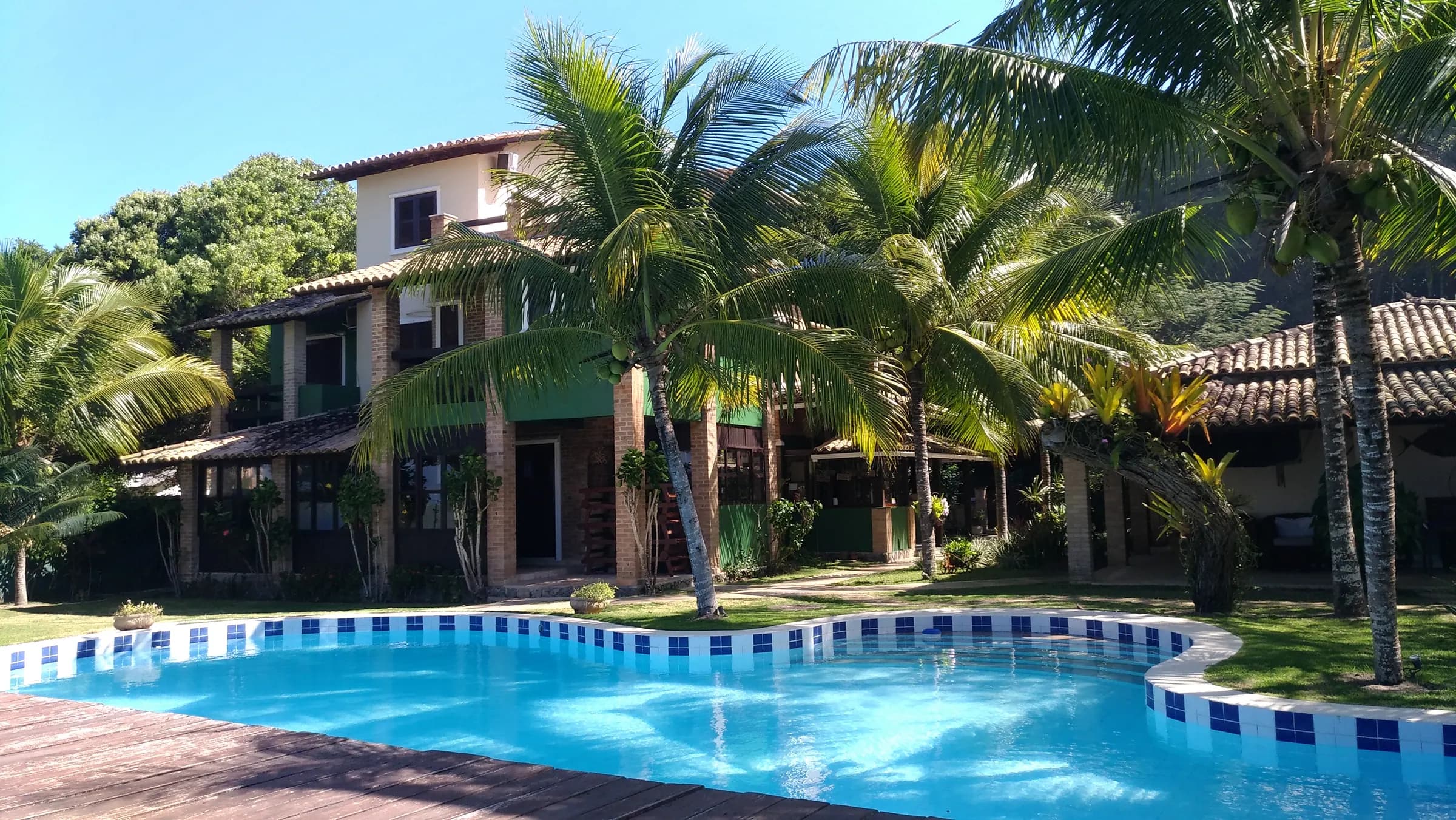 Piscina da Pousada Mayon com a casa principal e coqueiros